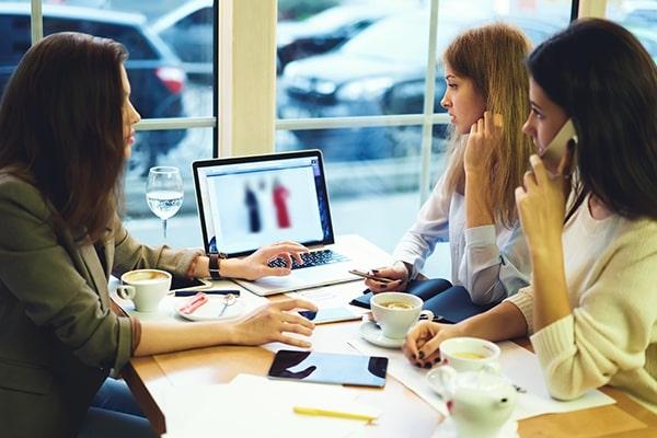 Three marketing agency staff around a desk having a discussion around a laptop